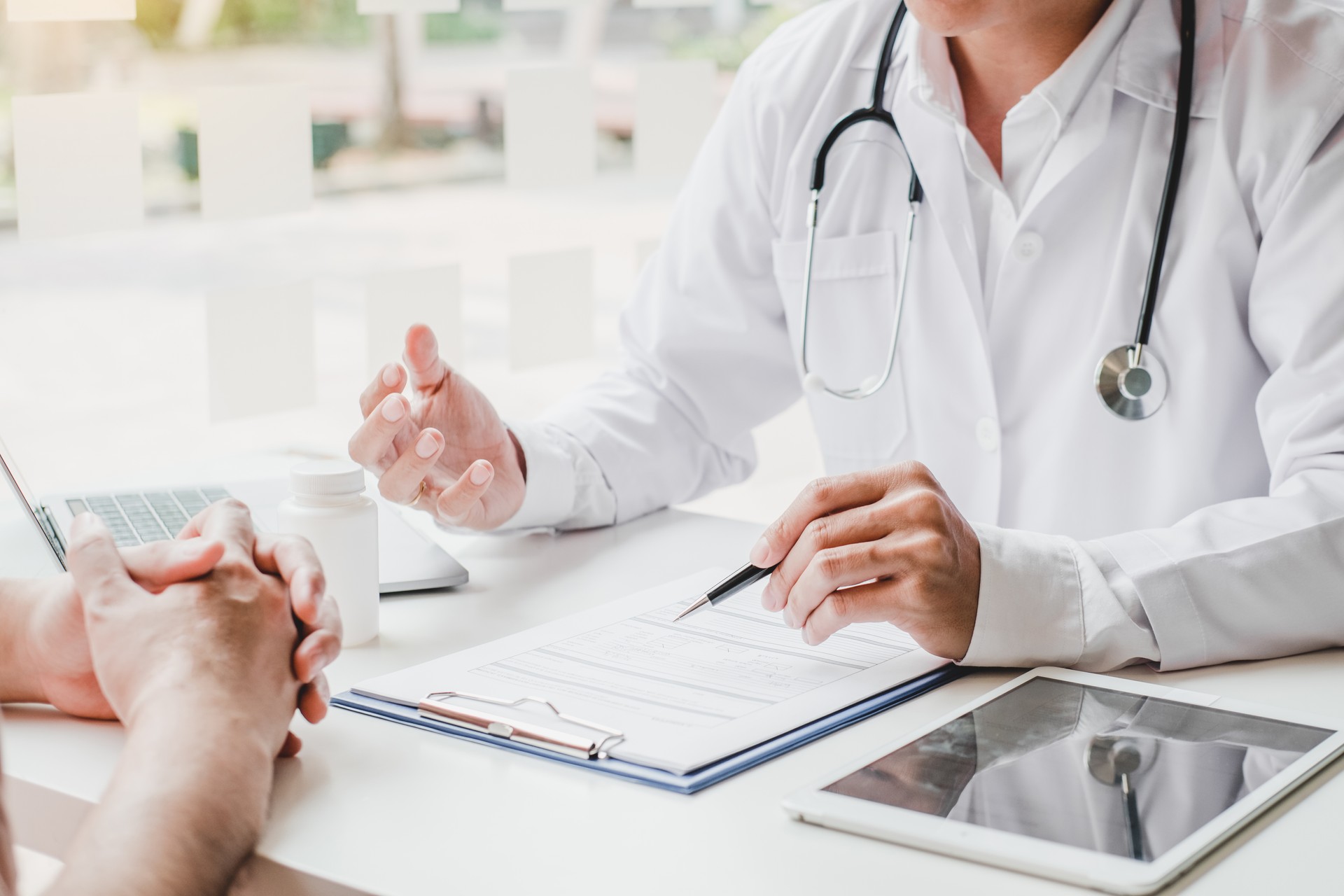 Doctors and patients consulting and diagnostic examining sit and talk. At the table near the window in the hospital medicine concept