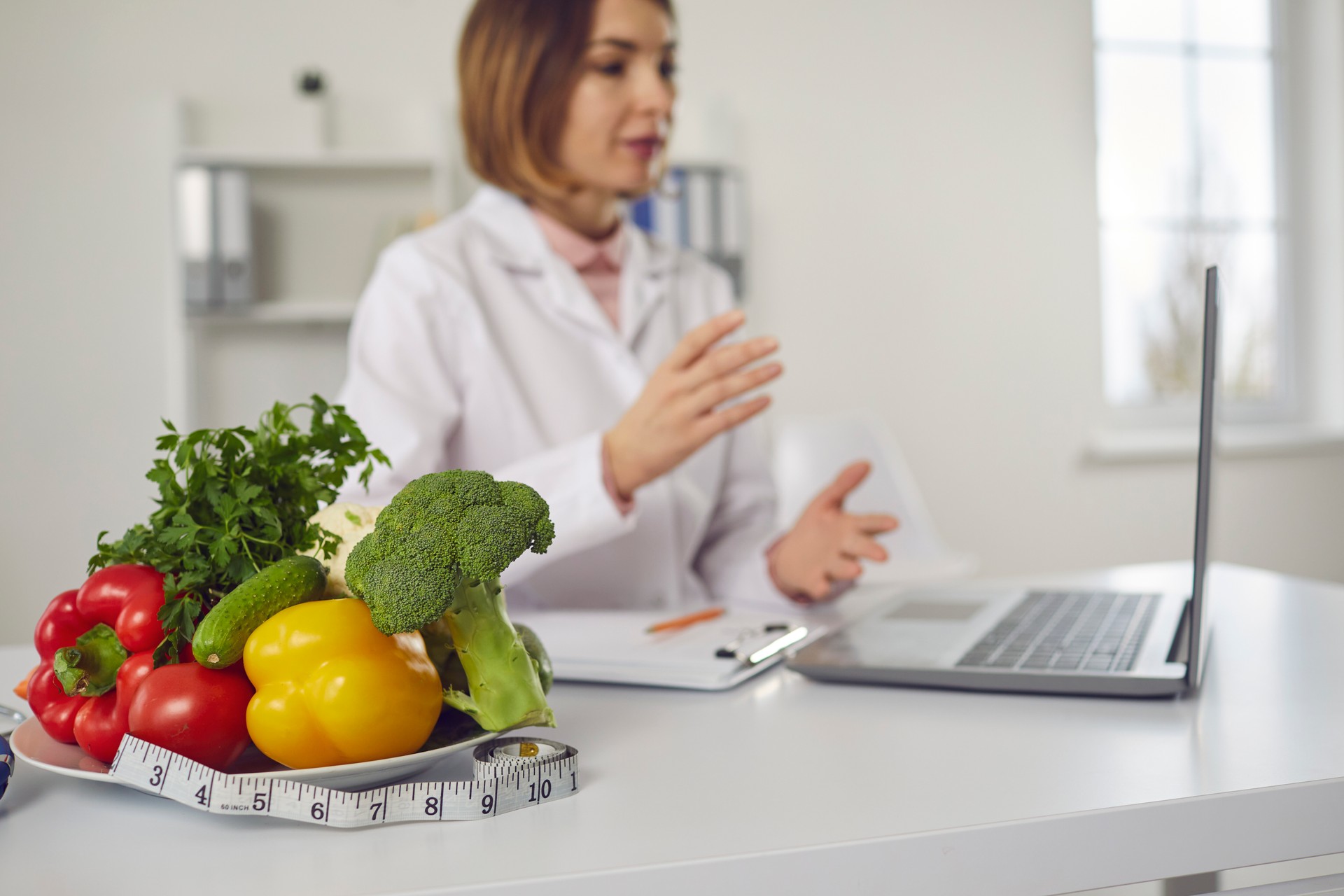 Vegetables and a measuring tape on the background of a nutritionist who provides online advice.