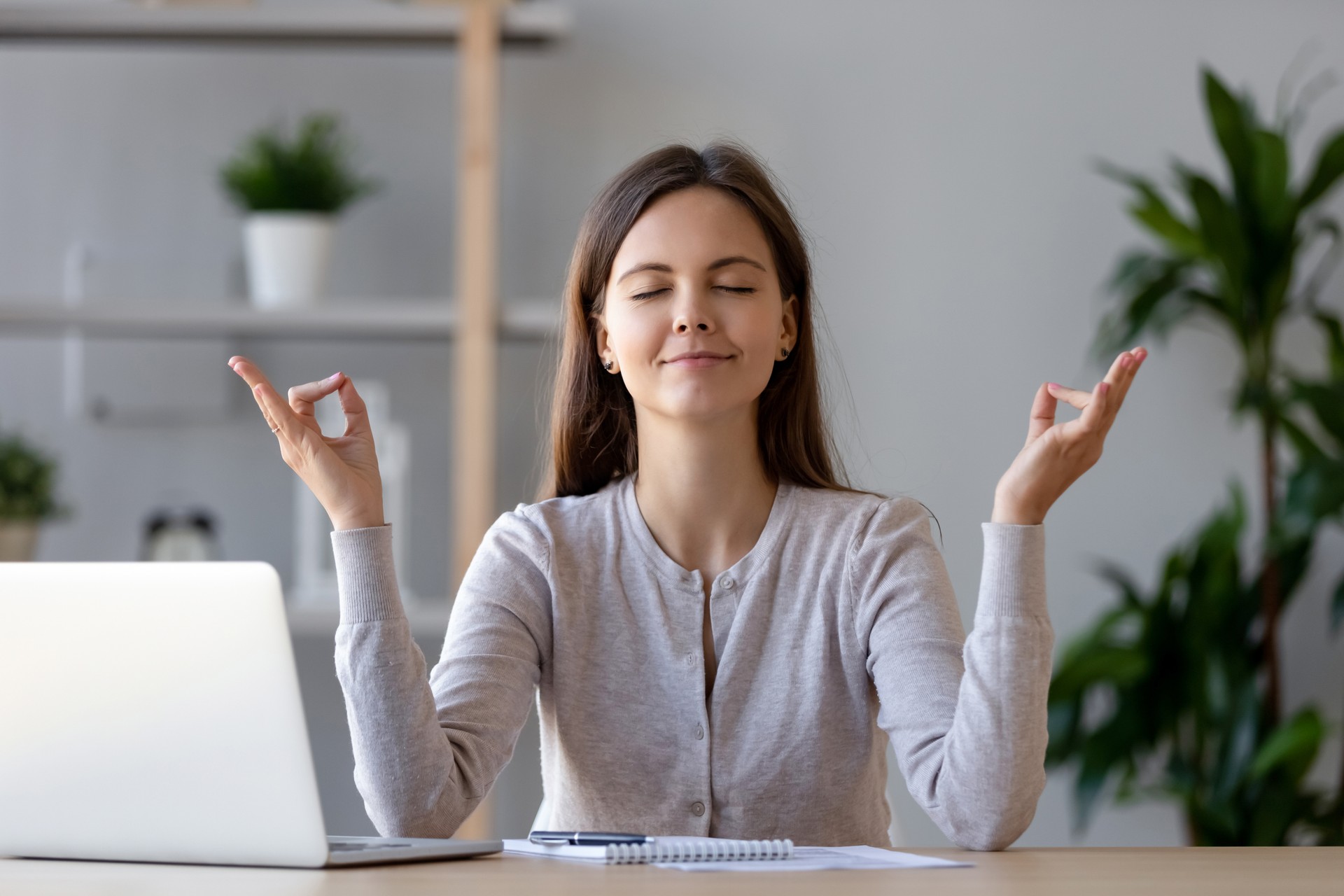 Calm young woman taking break doing yoga exercise at workplace